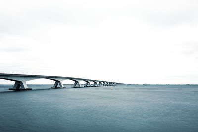 Bridge over sea against clear sky