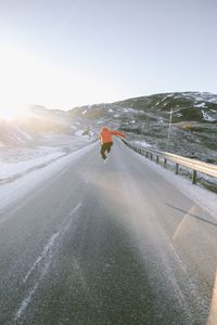 Rear view of person on road against sky during winter