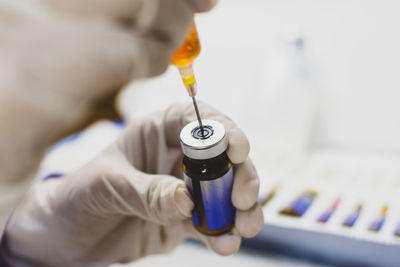 Cropped hands of doctor holding syringe and bottle