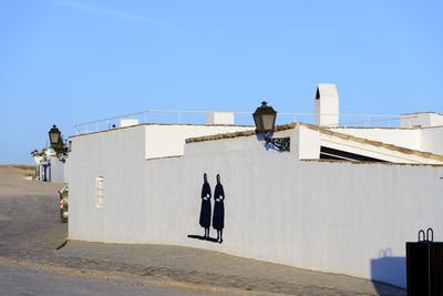 Rear view of man against white building against clear blue sky