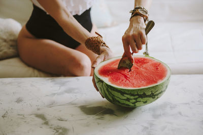 Midsection of woman having watermelon at home