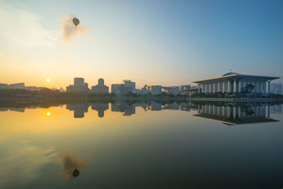 Reflection of buildings in lake against sky during sunset