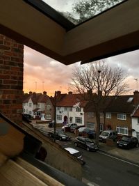 Cars on street amidst buildings against sky during sunset