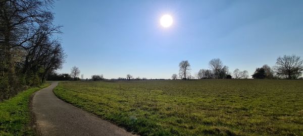 Road amidst field against sky