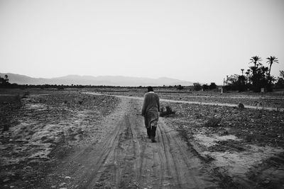 Full length of woman walking on landscape against clear sky