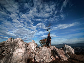 Man standing on rock against sky