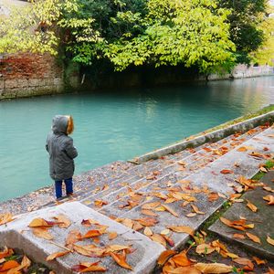 Rear view of a child standing by river