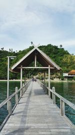 People walking on footbridge over sea