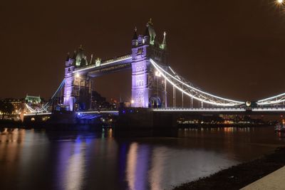 Illuminated suspension bridge over river at night