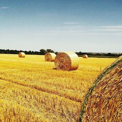 Hay bales on field against cloudy sky