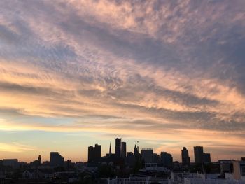 Buildings in city against cloudy sky at sunset