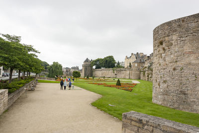 People walking on stone wall against sky