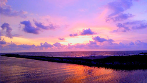 Scenic view of sea against dramatic sky during sunset