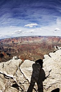 People standing on rock against cloudy sky