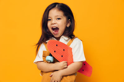 Portrait of young woman against yellow background