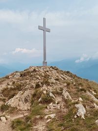 Low angle view of cross on mountain against sky