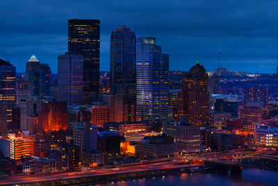 Illuminated buildings in city against sky at dusk