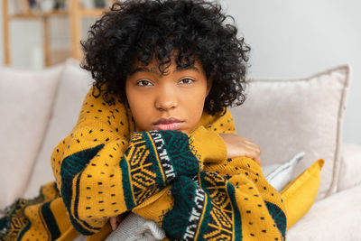 Portrait of young woman sitting on sofa at home