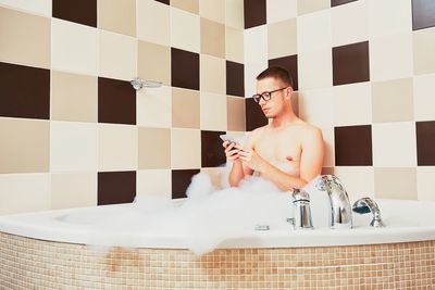 Man using smart phone in bathroom