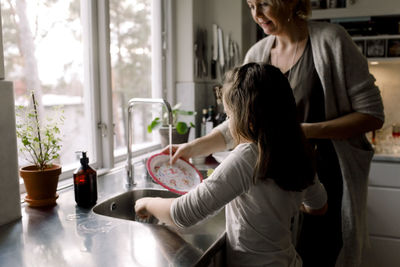 Daughter helping mother in kitchen at home