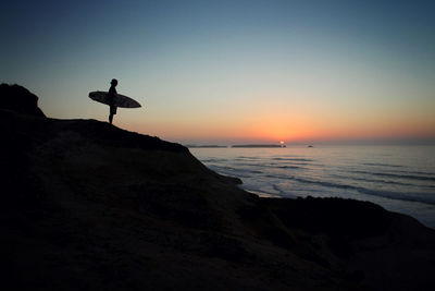 Silhouette person on beach against clear sky during sunset