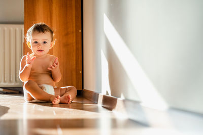 Portrait of boy looking away while sitting on floor at home