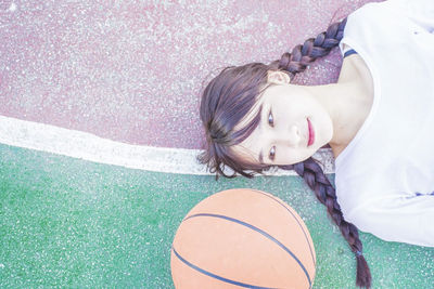 Directly above shot of young woman lying down at basketball court