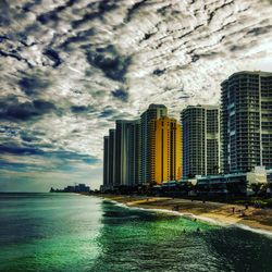 Buildings in city against cloudy sky