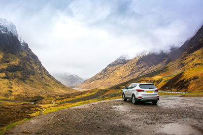 Cars on road by mountains against sky