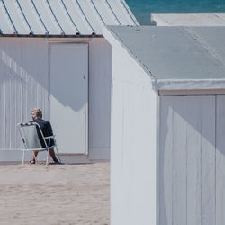 Rear view of man sitting on chair by house