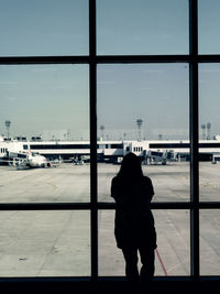 Rear view of man standing by window at airport