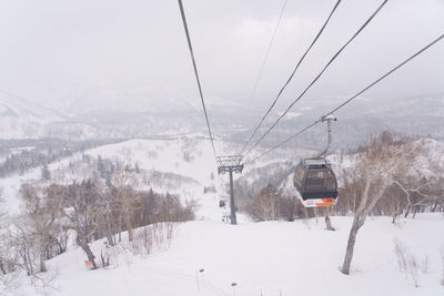 Ski lift over snow covered mountains against sky