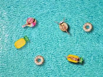 High angle view of female friends relaxing on pool rafts in sea