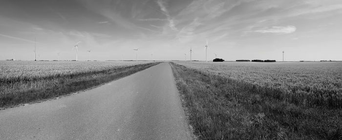 Road amidst field against sky