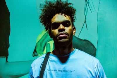 Portrait of young man standing against blue wall