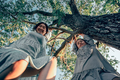 Whimsical heights, clad in season fabrics, asian girls laugh amidst branches, symbolizing spring