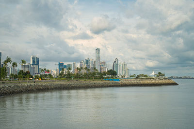 Panoramic view of bay and buildings against sky