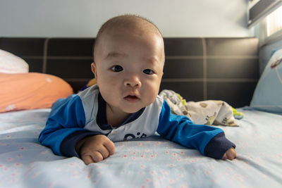 Portrait of cute baby lying on bed at home