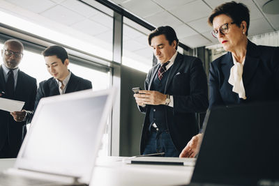 Business people working while standing in board room at office