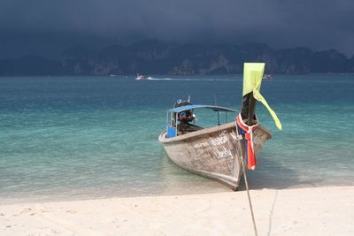 Boat moored on beach against sky