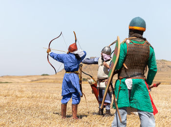 Rear view of people standing on field against clear sky