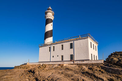 Moon-like slate rocks and lighthouse at idyllic cap de favaritx, menorca, balearic islands, spain