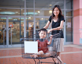Portrait of boy by mother sitting in shopping cart