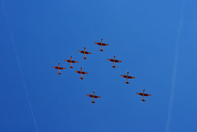 Low angle view of airshow against clear blue sky