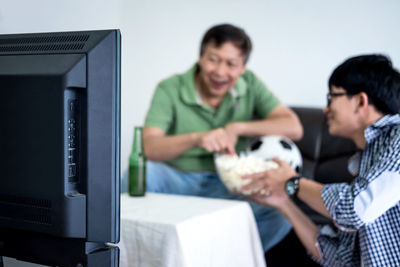 Family with food and drink watching sports on tv at home