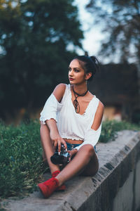 Young woman looking away while sitting on land