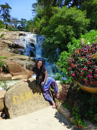 Portrait of young woman on rock against trees