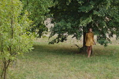 Rear woman standing against tree in forest