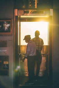 Rear view of man standing by window