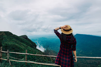 Woman standing on railing against mountain